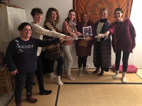 Un groupe de femmes en formation de sonothérapie se tient en cercle dans une salle chaleureuse, tenant ensemble des diapasons tendus vers le centre. L’ambiance est conviviale et concentrée, illustrant un moment de pratique collective lors d’une formation dans le Nord de la France.