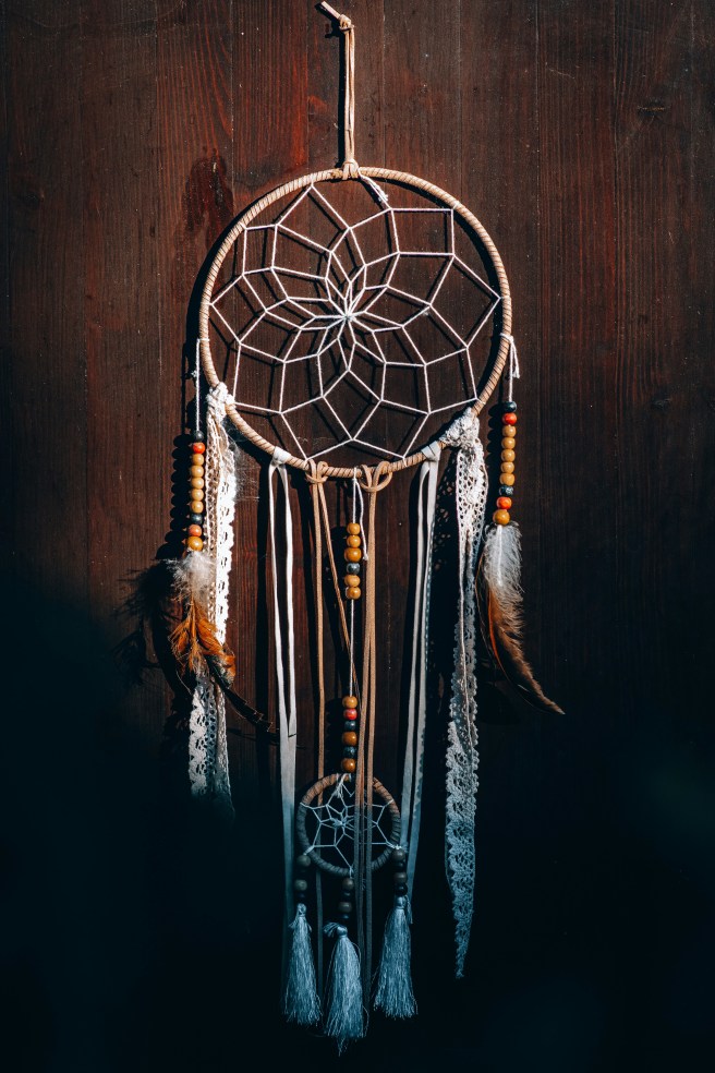 attrape rêves suspendu à un mur en bois, symbole du chamanisme amérindien emprunté par votre guérisseuse chamanique à lille
