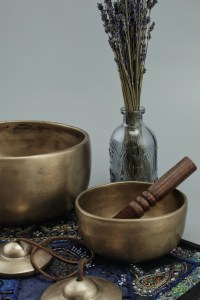 Cymbales et bols tibétains disposés sur un autel à côté d'un bouquet de lavande dans un vase